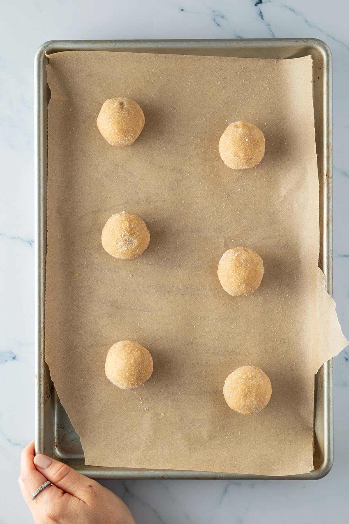 In Zucker gew&auml;lzte Teig-Kugel auf einem Blech.