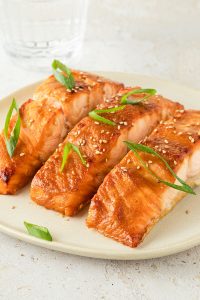 Drei Miso-Lachsfilets auf einem Teller.