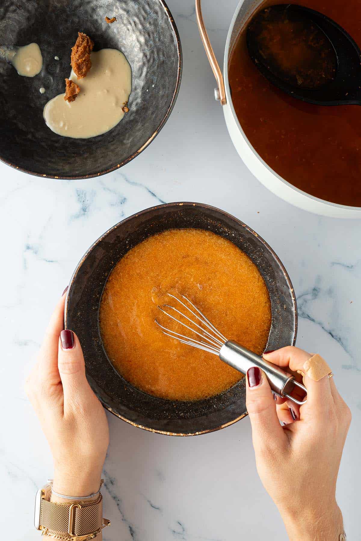 Ramenbr&uuml;he wird in einer Sch&uuml;ssel mit Miso und Tahini verr&uuml;hrt, daneben eine zweite Sch&uuml;ssel mit Miso Paste und Tahini und der Topf mit der Ramenbr&uuml;he.