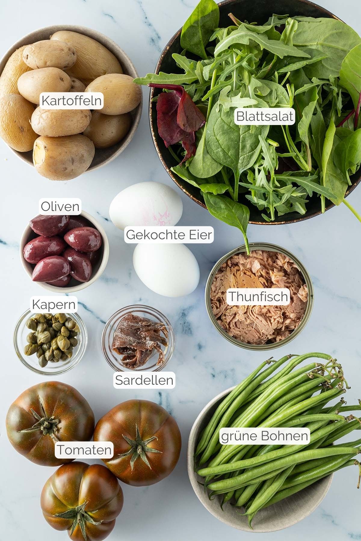 Foto aller Zutaten mit jeweiligen Textbeschriftungen, die f&uuml;r den Nizza Salat ben&ouml;tigt werden.