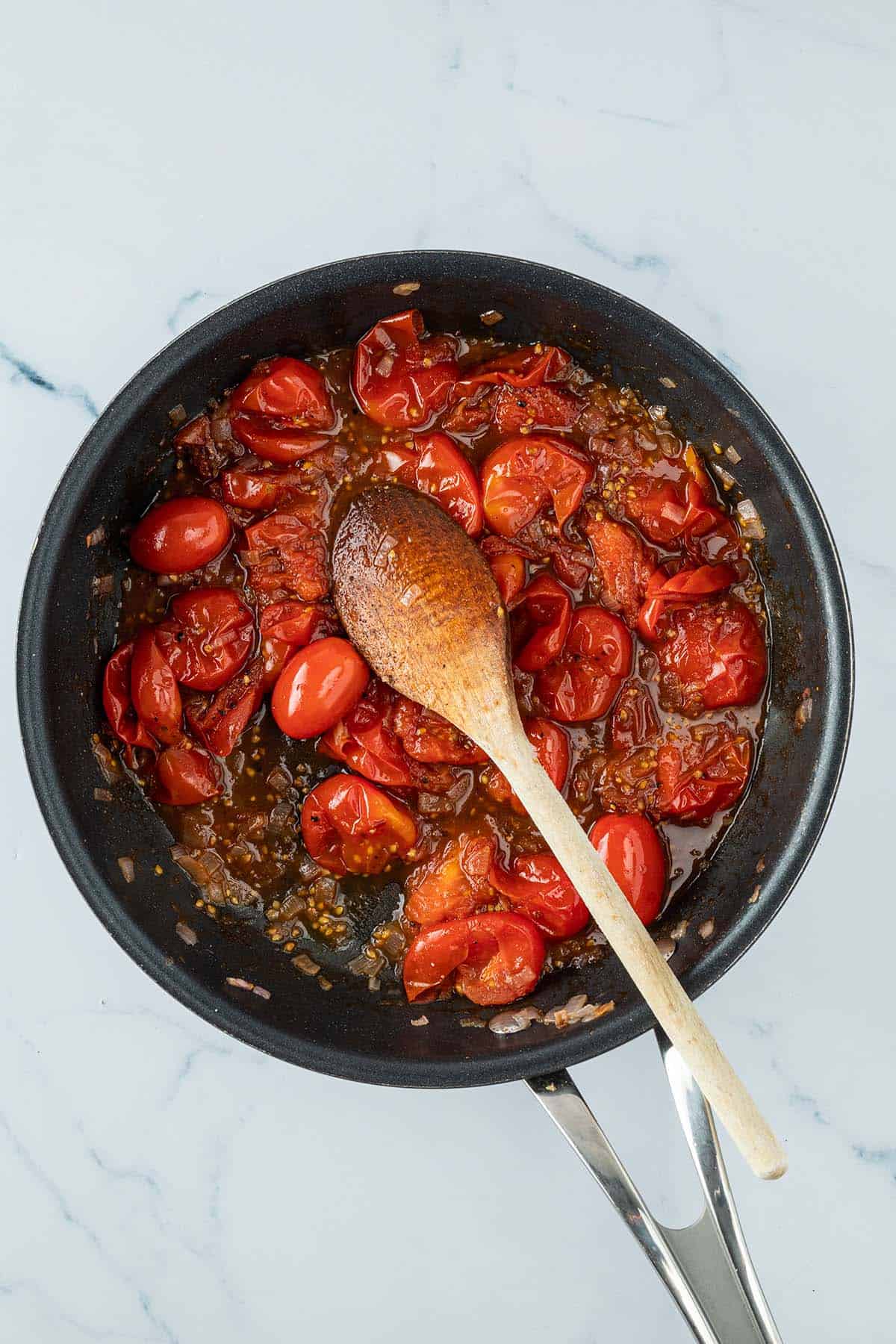 Fertiges Tomaten-Balsamico-Dressing in einer Pfanne mit einem Kochl&ouml;ffel.