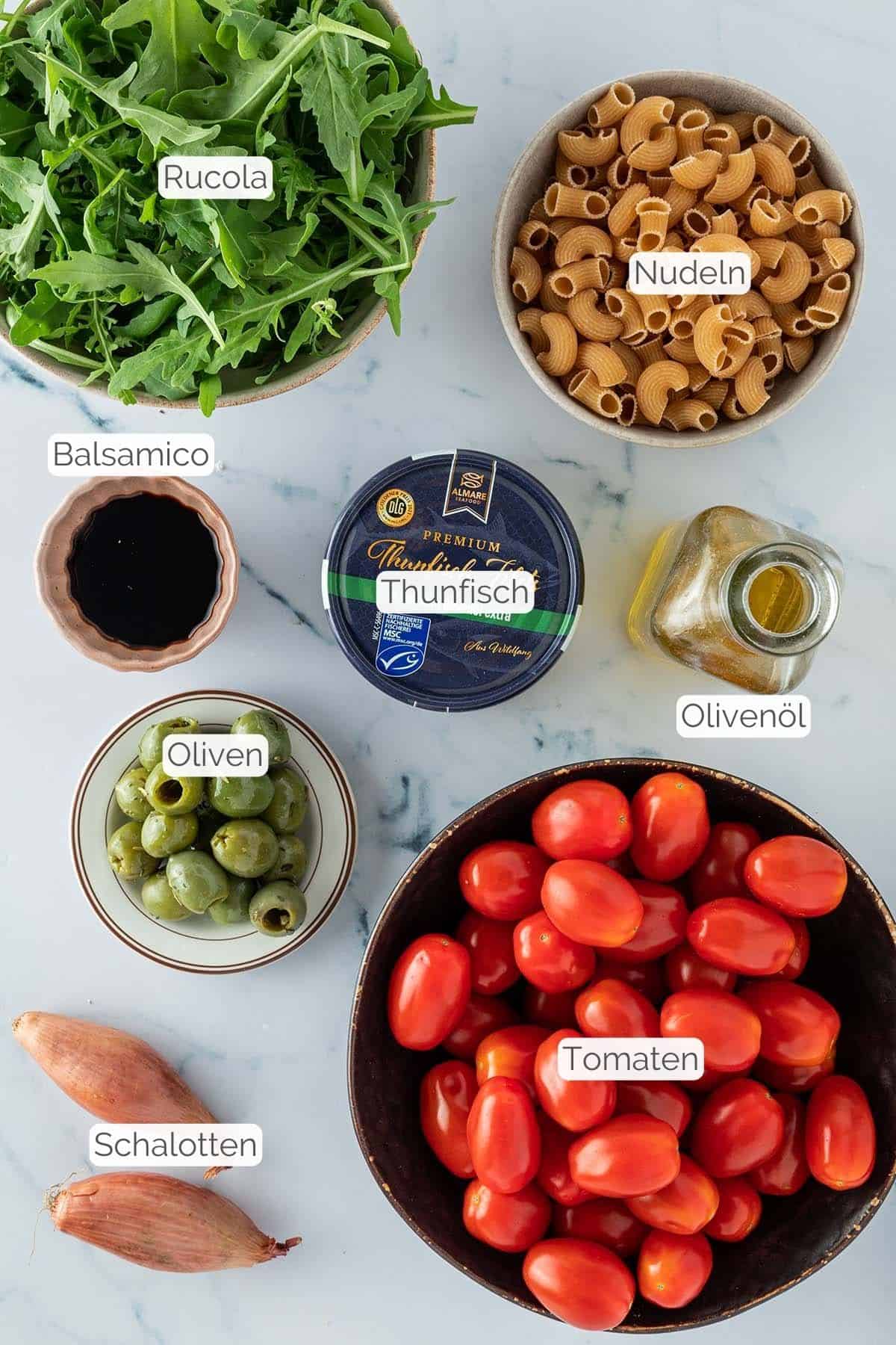Foto aller Zutaten mit jeweiligen Textbeschriftungen, die f&uuml;r einen italienischen Nudelsalat im Glas ben&ouml;tigt werden.
