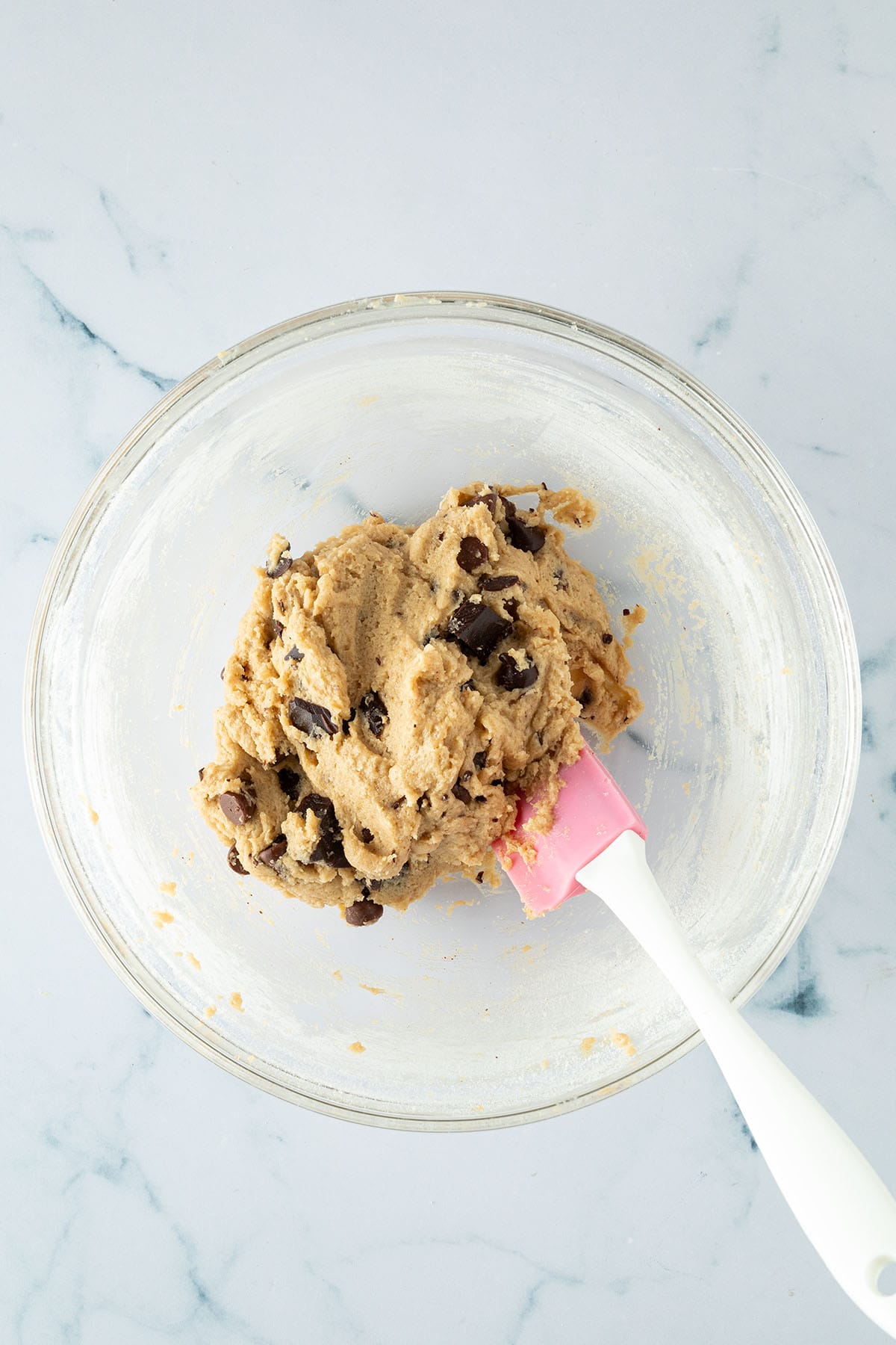 Chocolate Chip Cookie-Teig mit eingearbeiteten Schokodrops in einer Glassch&uuml;ssel.