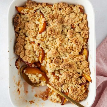 Auflaufform mit Obst Crumble auf einem hellen Hintergrund.