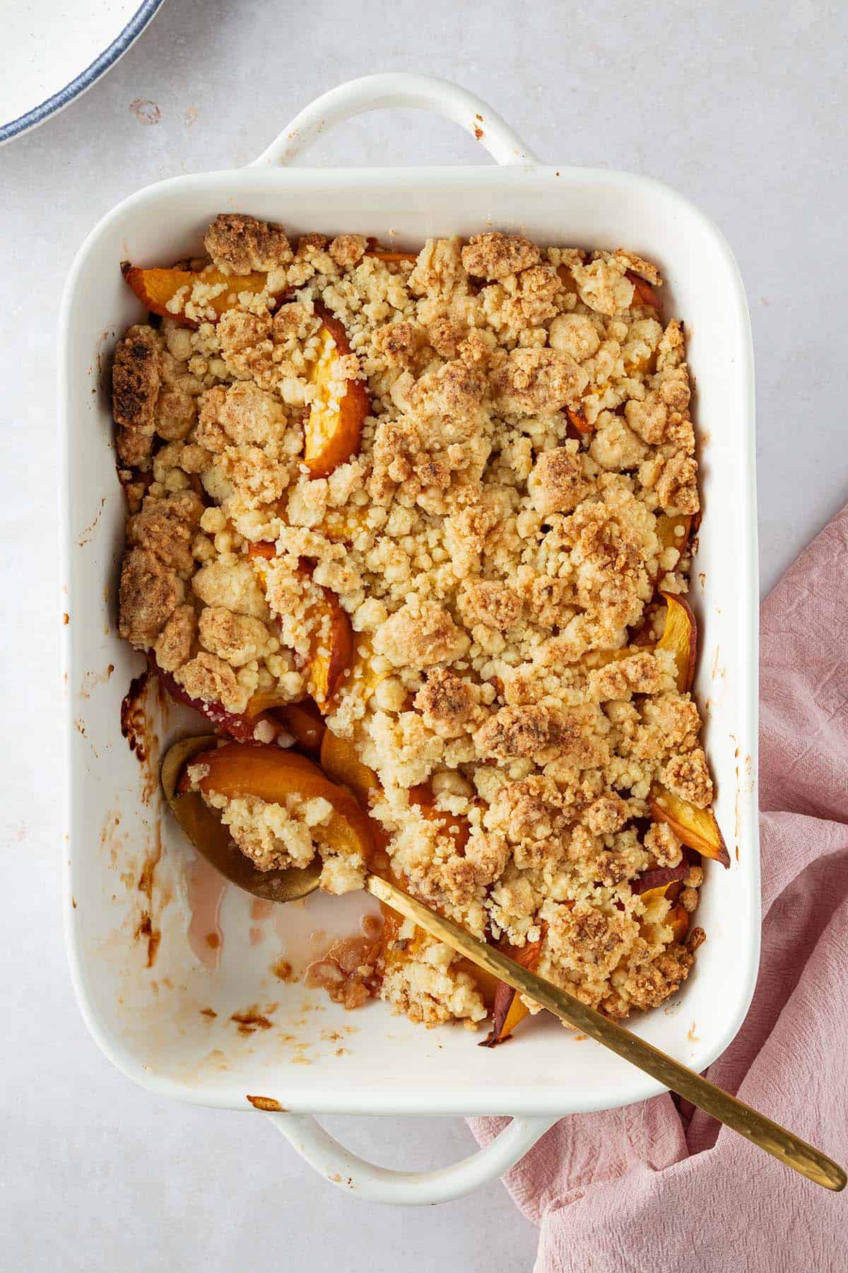 Auflaufform mit Obst Crumble auf einem hellen Hintergrund.