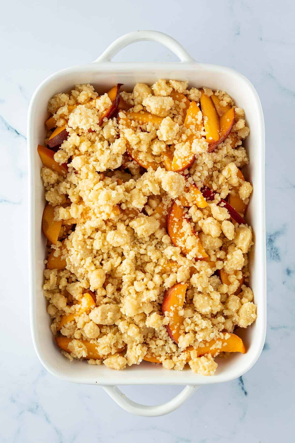 Obst Crumble in einer Auflaufform vor dem Backen im Ofen.