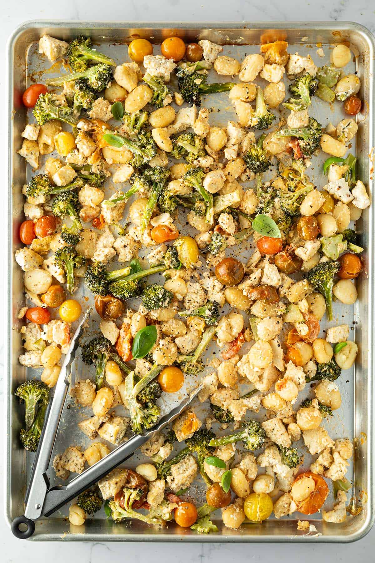 Ein Blech auf dem Gnocchi, Tofu und Gem&uuml;se aus dem Ofen mit einer cremigen Frischk&auml;sesauce vermischt werden.