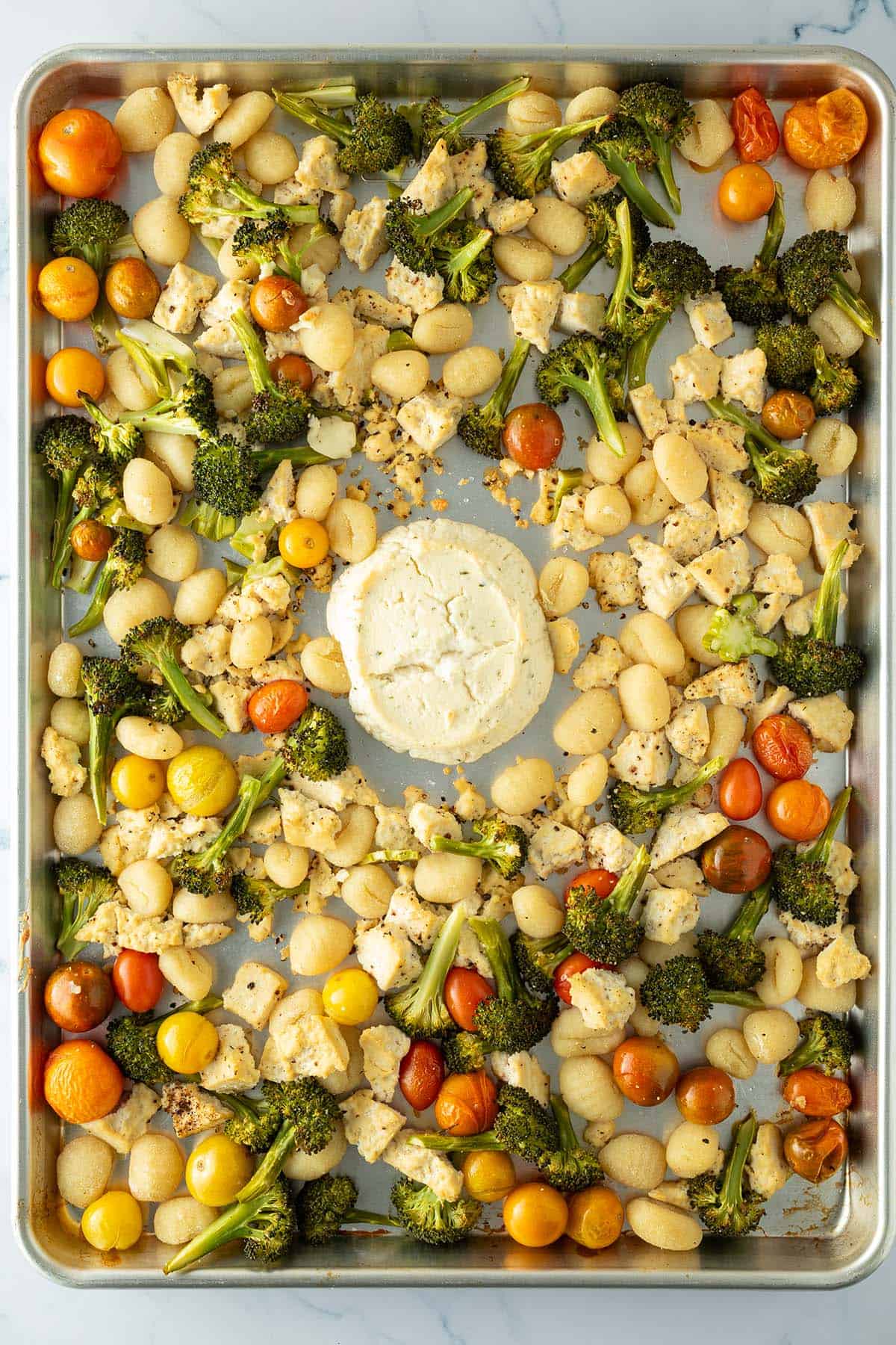 Ein Blech mit im Ofen gebackene Gnocchi, Gem&uuml;se und Tofu, in der Mitte ein im Ofen gebackener Frischk&auml;se.