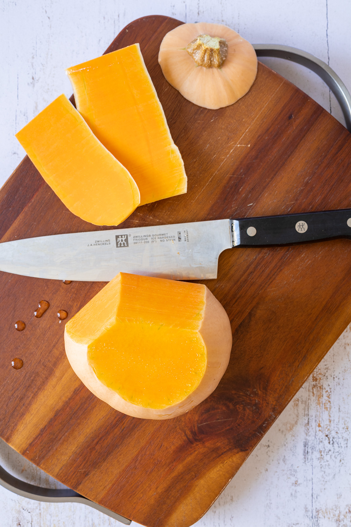 Von einem Butternutk&uuml;rbis wird mit einem Messer die Schale abgeschnitten.