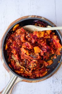 Im Ofen weich gegartes K&uuml;rbisgem&uuml;se wird in einer Pfanne mit Pesto und passierten Tomaten verfeinert.