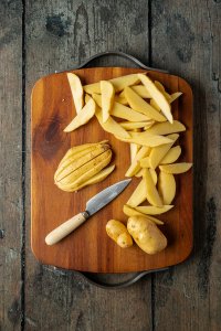 Kartoffeln werden in d&uuml;nne, l&auml;ngliche Spalten geschnittenen.
