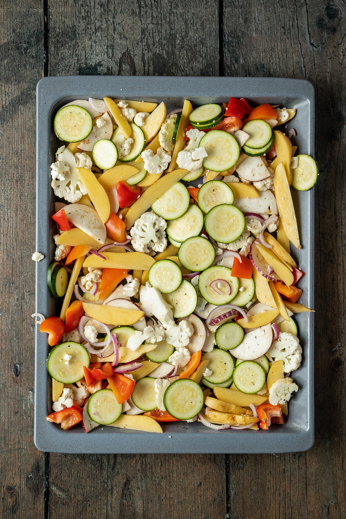 Gem&uuml;se und Kartoffelspalten vor dem Garten im Ofen auf einem Backblech.