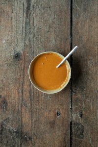 Eine kleine Sch&uuml;ssel mit einer Erdnusssauce drin auf einem dunklen Holzuntergrund.