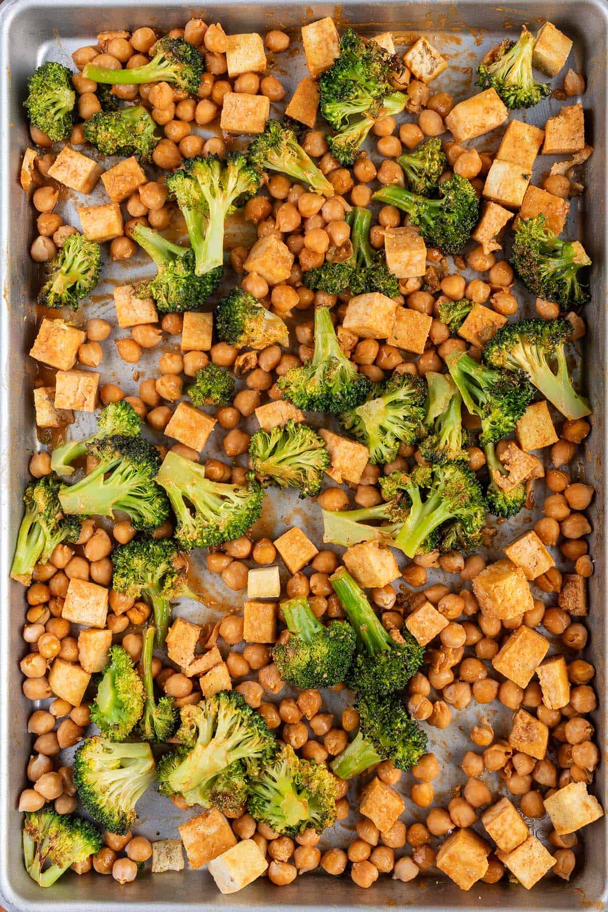 Brokkoli, Tofu und Kichererbsen knusprig ger&ouml;stet auf einem Blech.