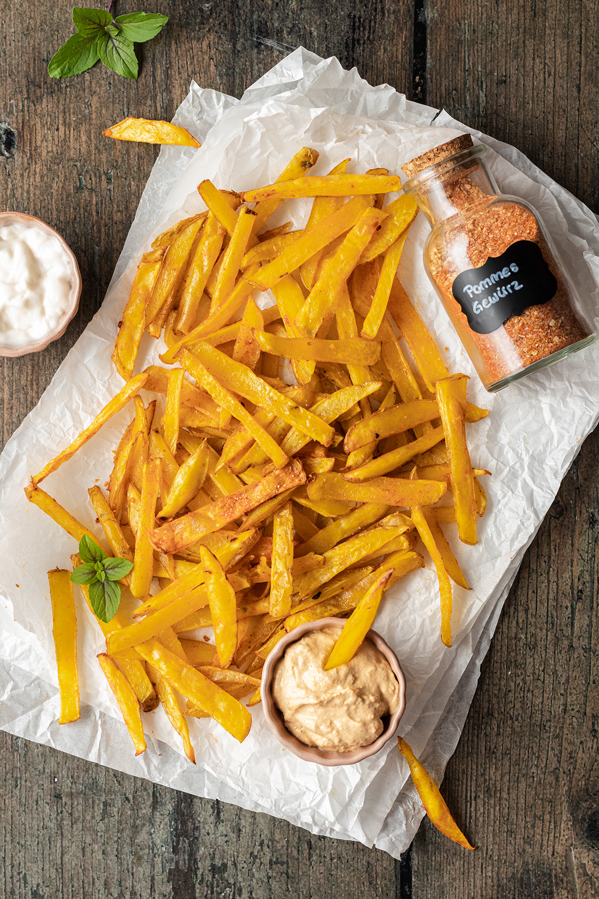 Eine Portion selbst gemachter Pommes mit zweierlei Dips, daneben ein Gl&auml;schen mit selbstgemachten Pommes Gew&uuml;rz.