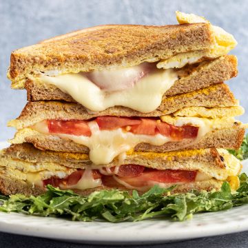 Ein Stapel von Sandwiches mit geschmolzenem K&auml;se und Tomaten.