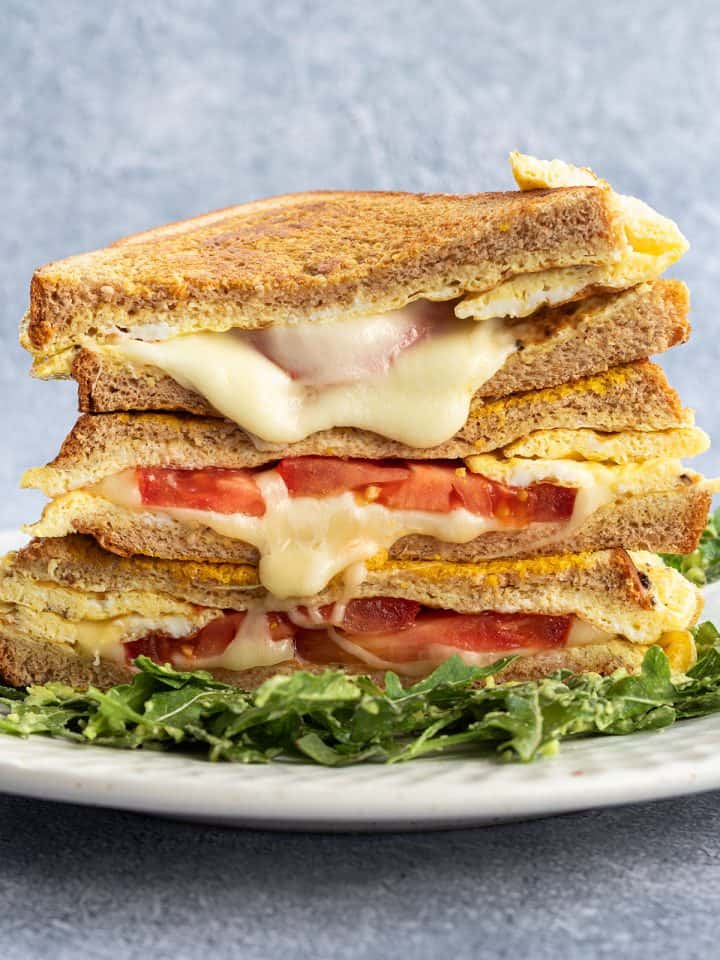 Ein Stapel von Sandwiches mit geschmolzenem K&auml;se und Tomaten.