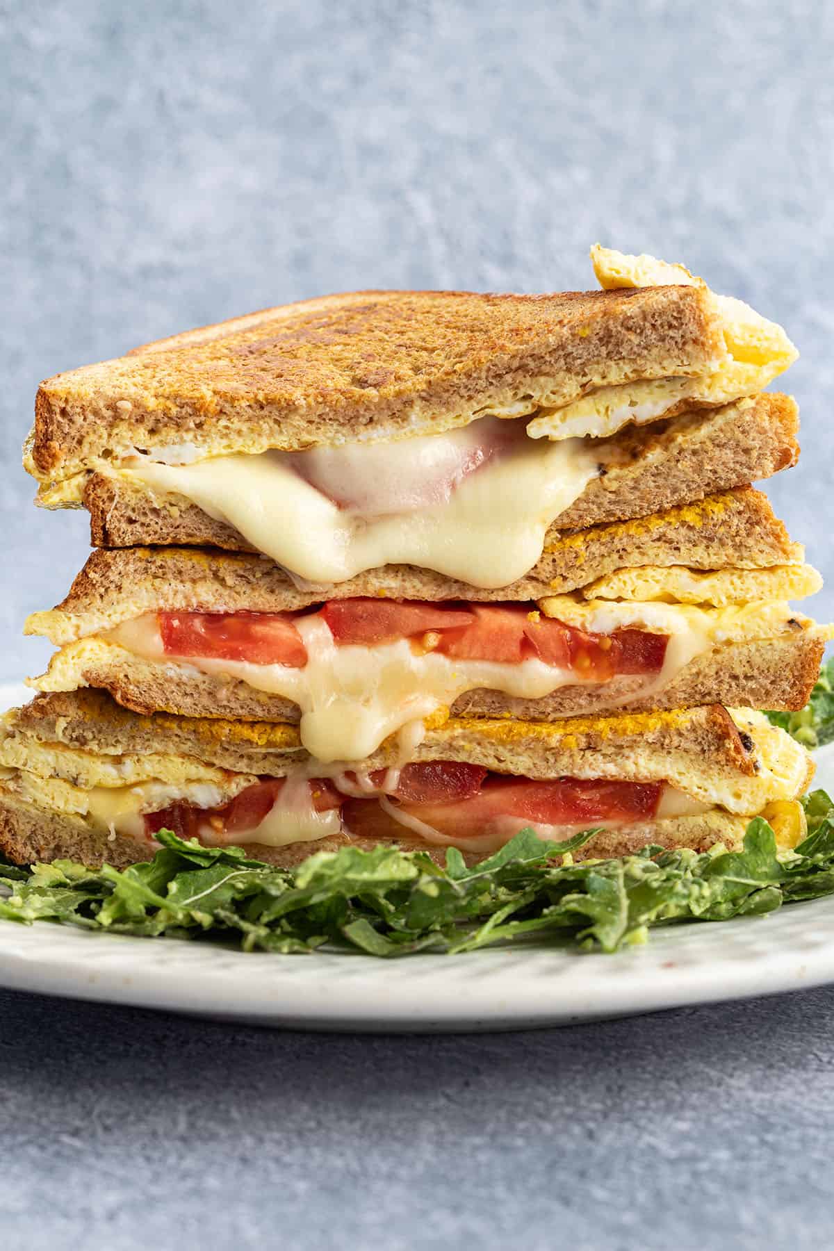 Ein Stapel von Sandwiches mit geschmolzenem K&auml;se und Tomaten.