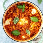 Vogelperspektive auf einen Topf mit einer One Pot Lasagne mit geschmolzenem Mozzarella und frischem Basilikum, Deko im Bildrand.