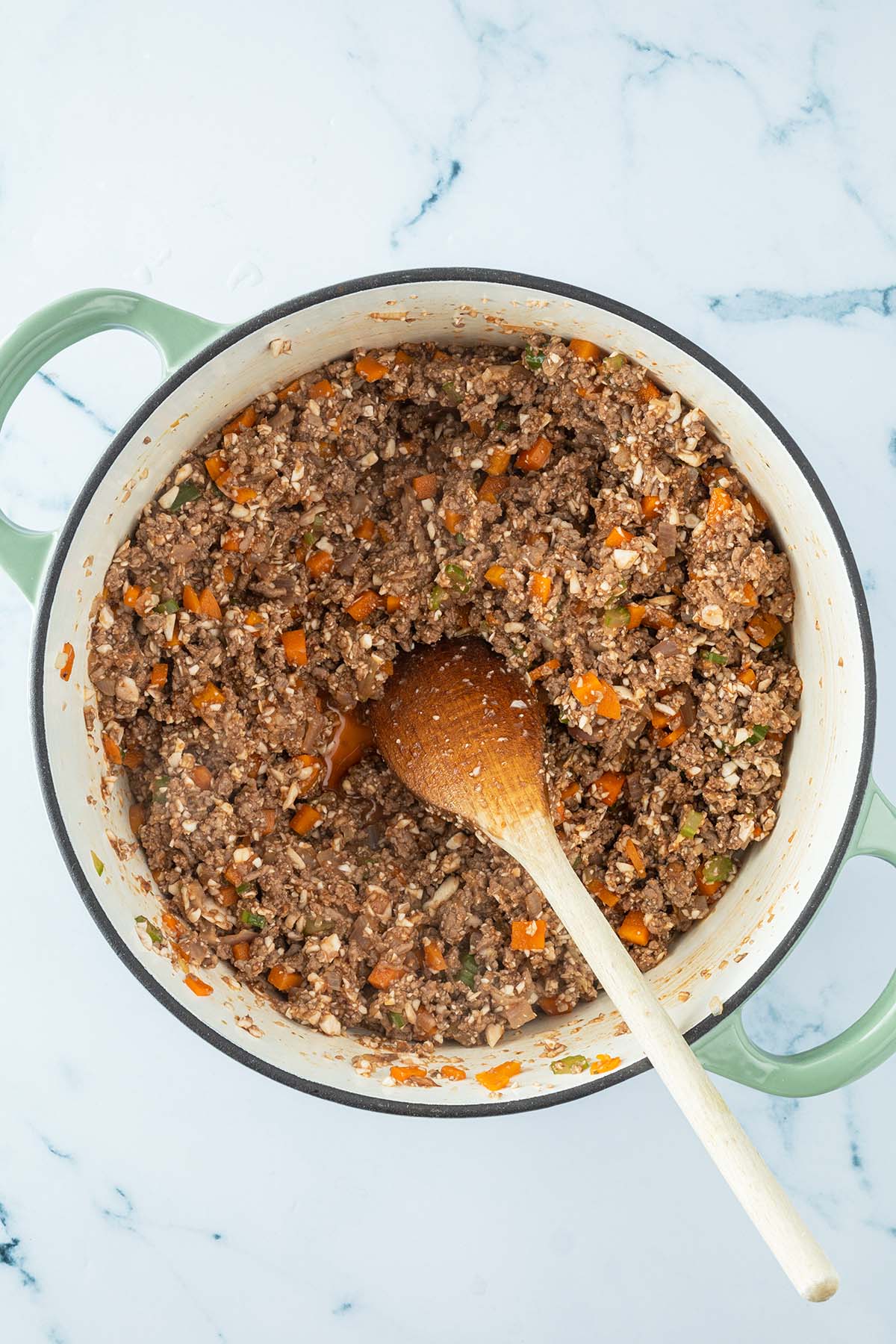 Vogelperspektive auf einen Topf mit gebratenem Hackfleisch, ganz fein zerkleinerten Champignons und Gem&uuml;se.