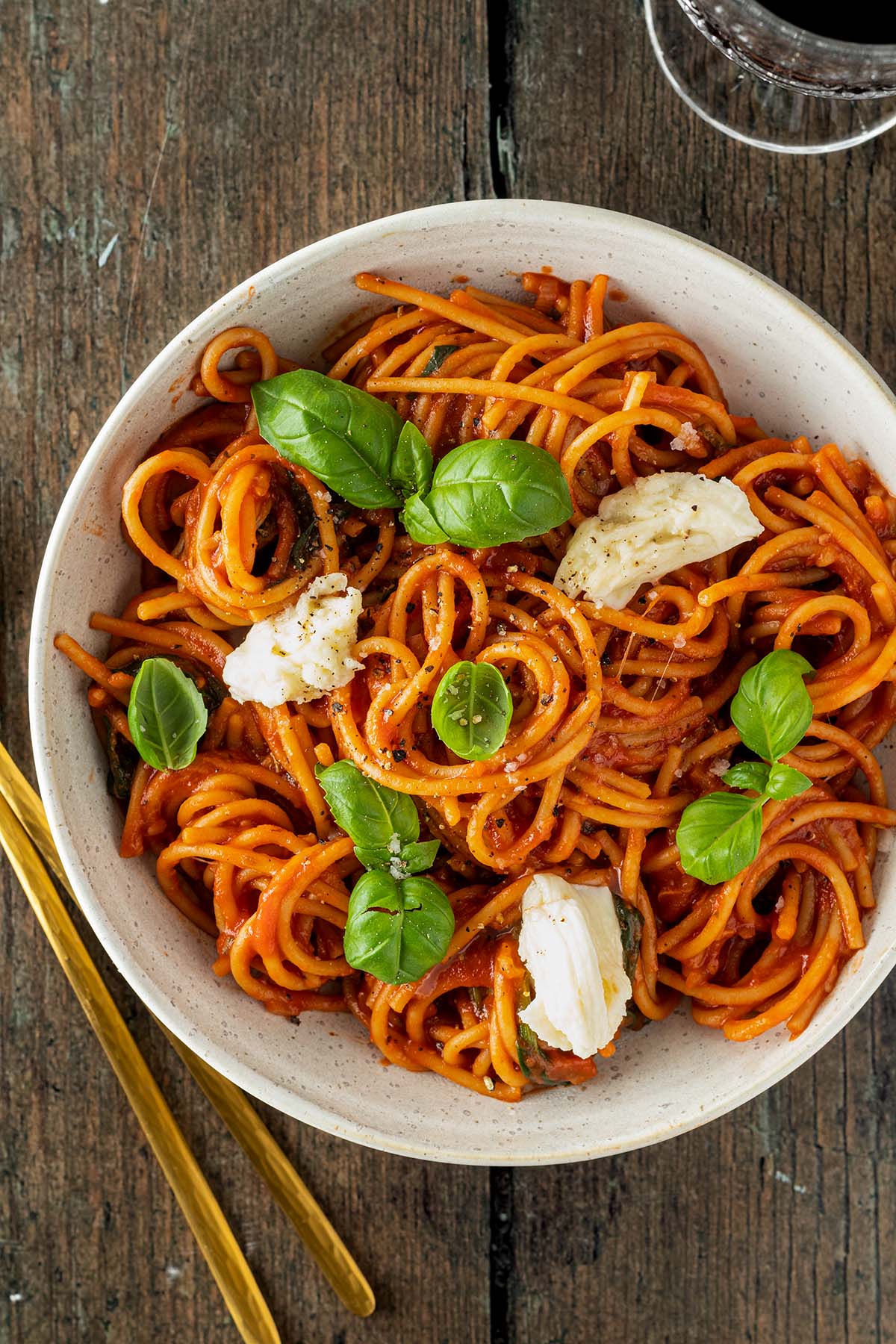 Teller Spaghetti in Tomatensauce mit frischem Mozzarella und Thunfisch auf einem Holzuntergrund.