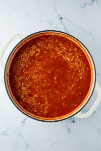Gekochter Orzo in einer Pfanne mit Tomatensauce.