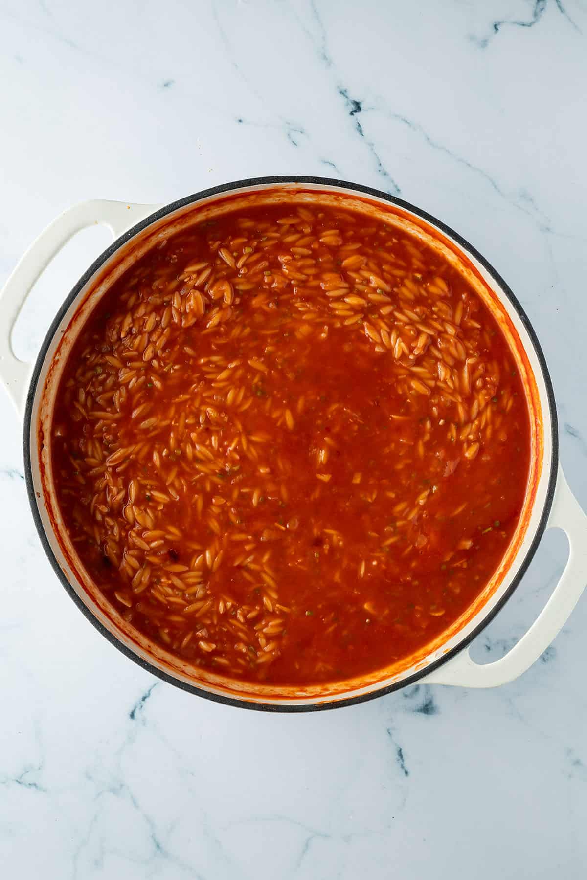 Gekochter Orzo in einer Pfanne mit Tomatensauce.