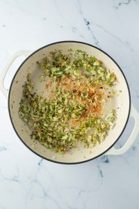 Zwiebeln, Knoblauch und Petersilienst&auml;ngel werden mit Chiliflocken angebraten.