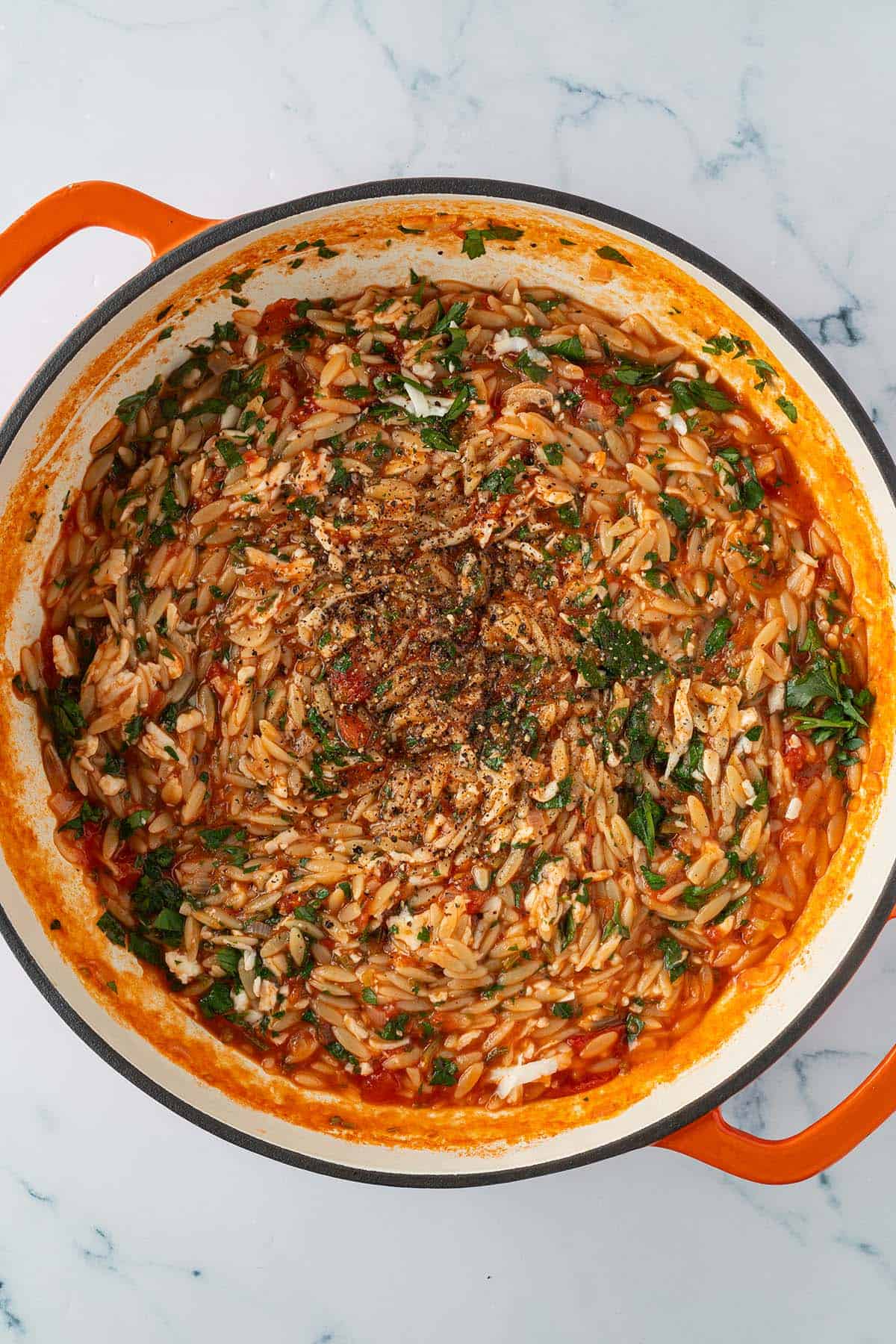 Fertig gekochtes Orzo Risotto unter das der geriebene Halloumi-K&auml;se und die gehackten Petesilienbl&auml;tter ger&uuml;hrt wurde.