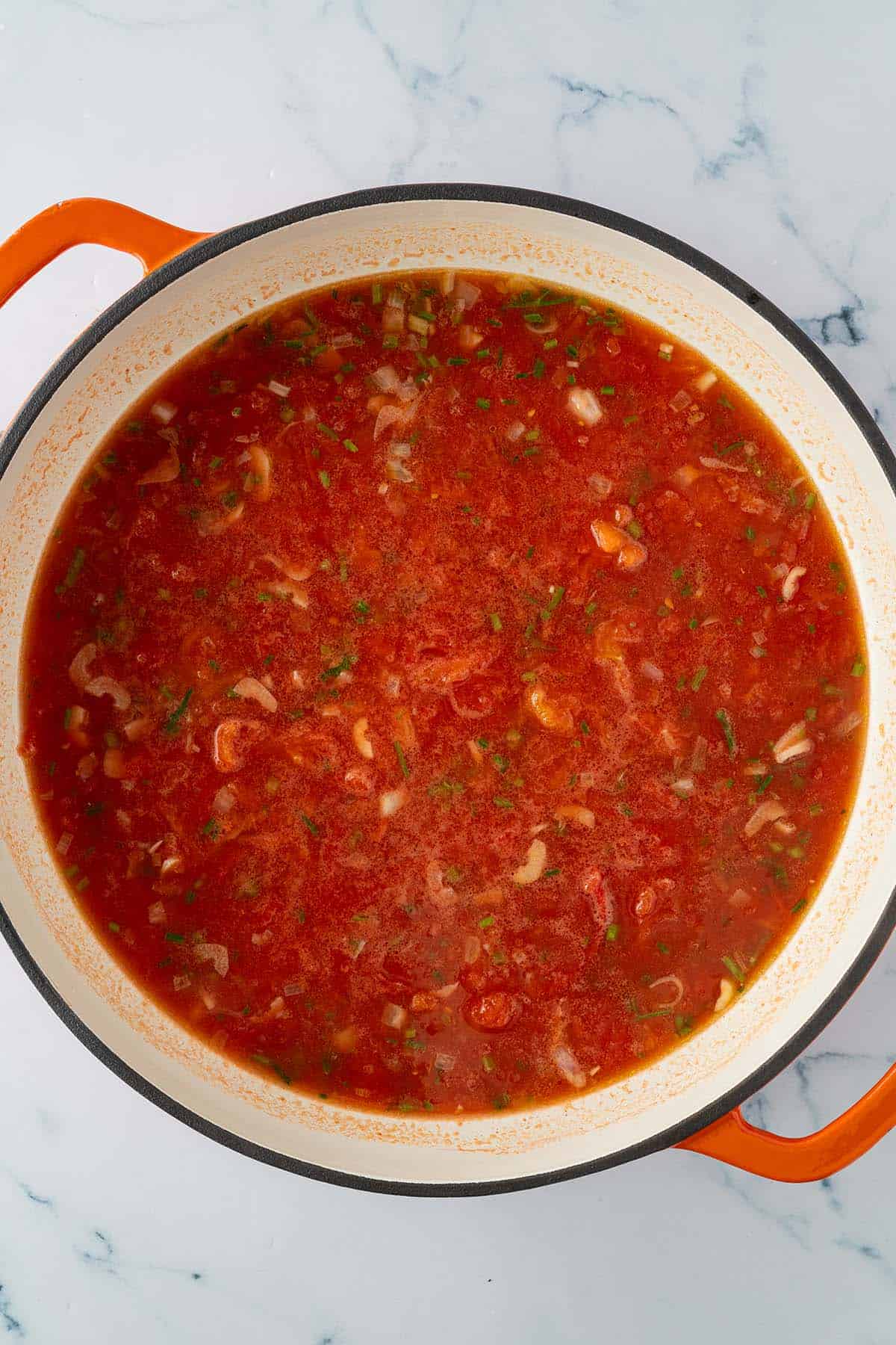 Orzo Nudeln werden in der Tomatensauce gekocht.