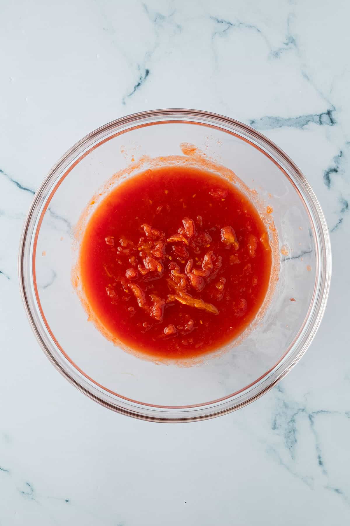 Gesch&auml;lte Tomaten aus der Dose wurde in einer Sch&uuml;ssel mit den H&auml;nden zerdr&uuml;ckt.