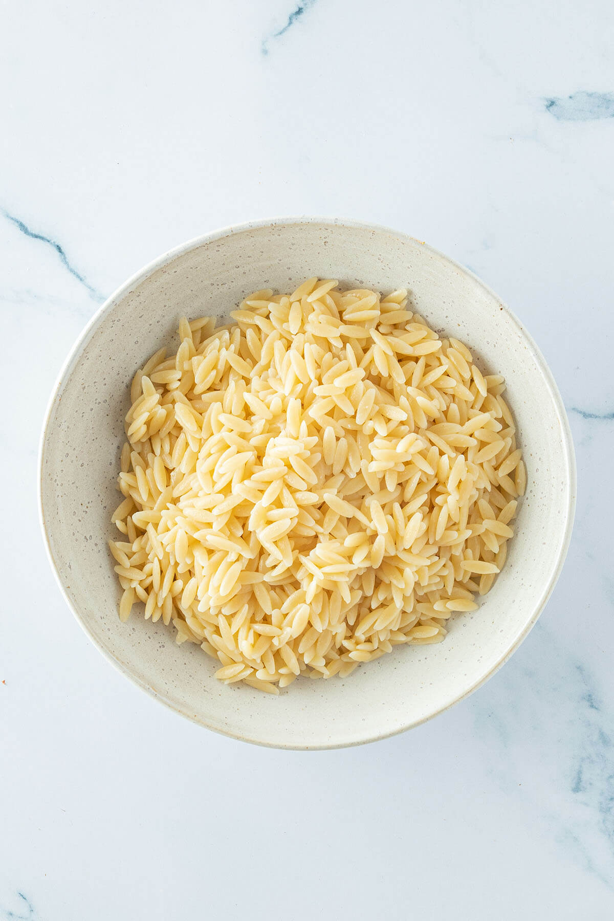 Gekochte Orzo Nudeln in einem beigen Teller.