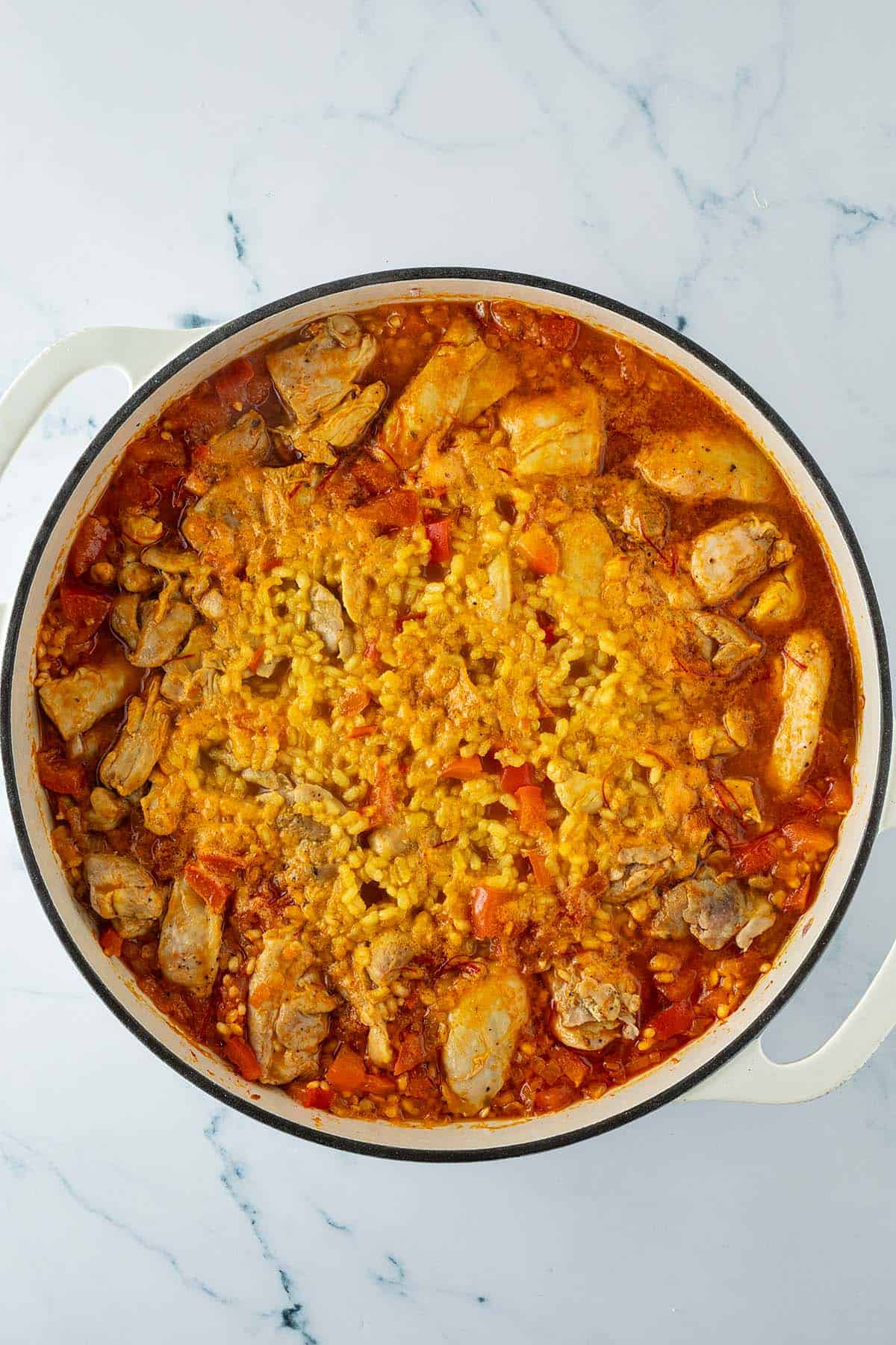Paella mit H&auml;hnchen und Safranreis w&auml;hrend des Garens, bevor die Garnelen hinzugef&uuml;gt werden.