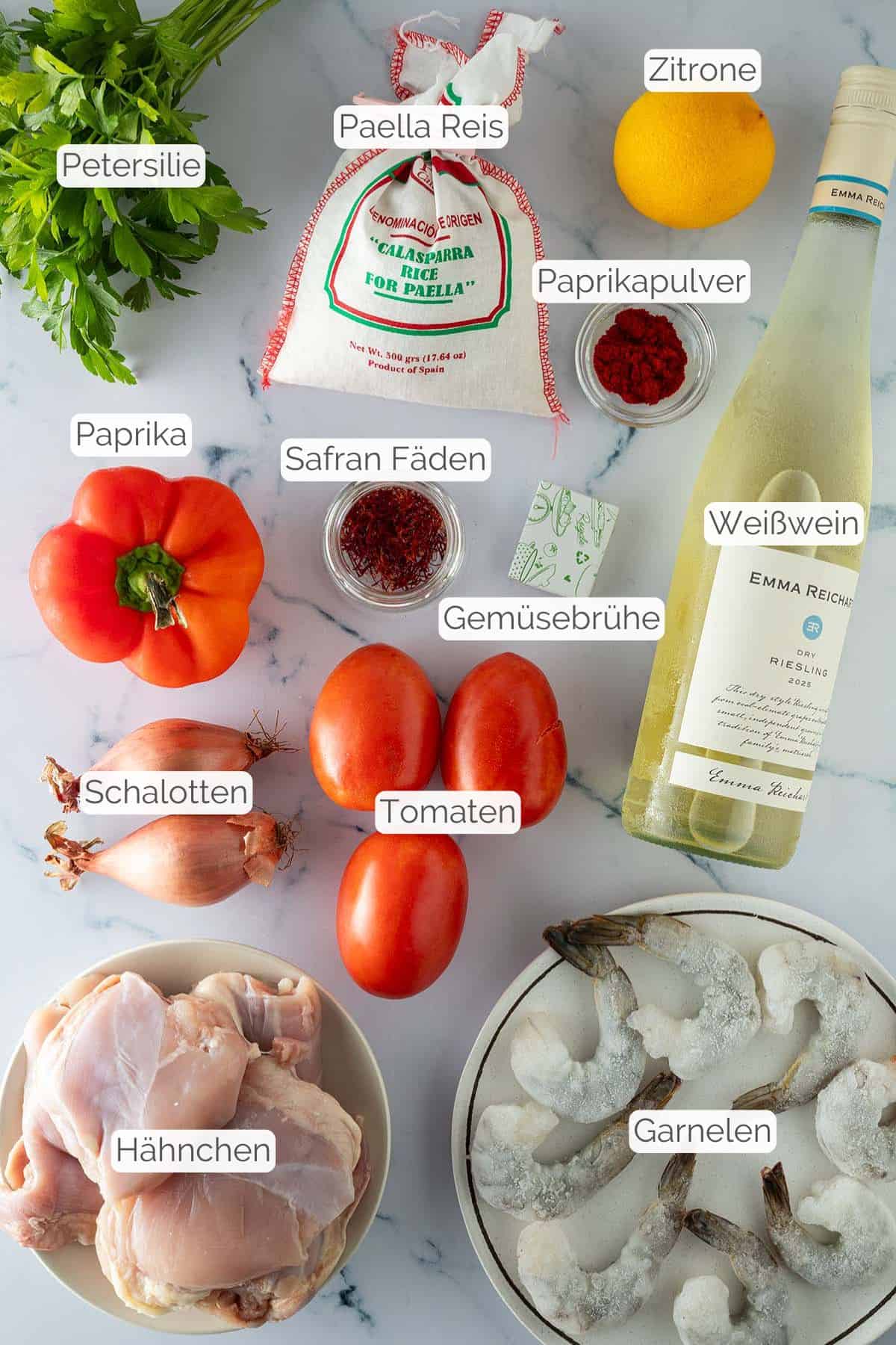 Alle Zutaten mit jeweiligen Textbeschriftungen, die f&uuml;r die Paella mit H&auml;hnchen und Reis ben&ouml;tigt werden.
