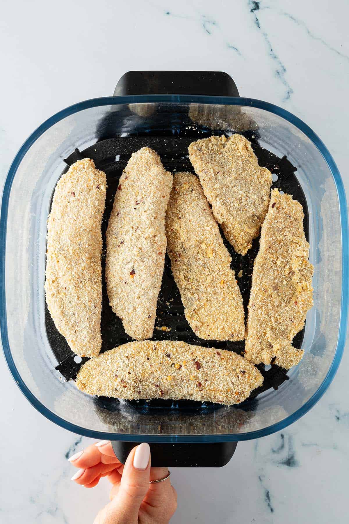 Rohe, panierte Fischfilets im Airfryer-Korb.