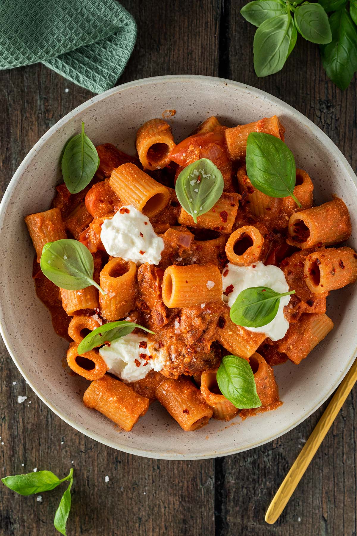 Rigatoni Nudeln in einer cremigen Ricotta-Tomaten-Sauce mit frischem Basilikum und Ricotta-Tupfen.
