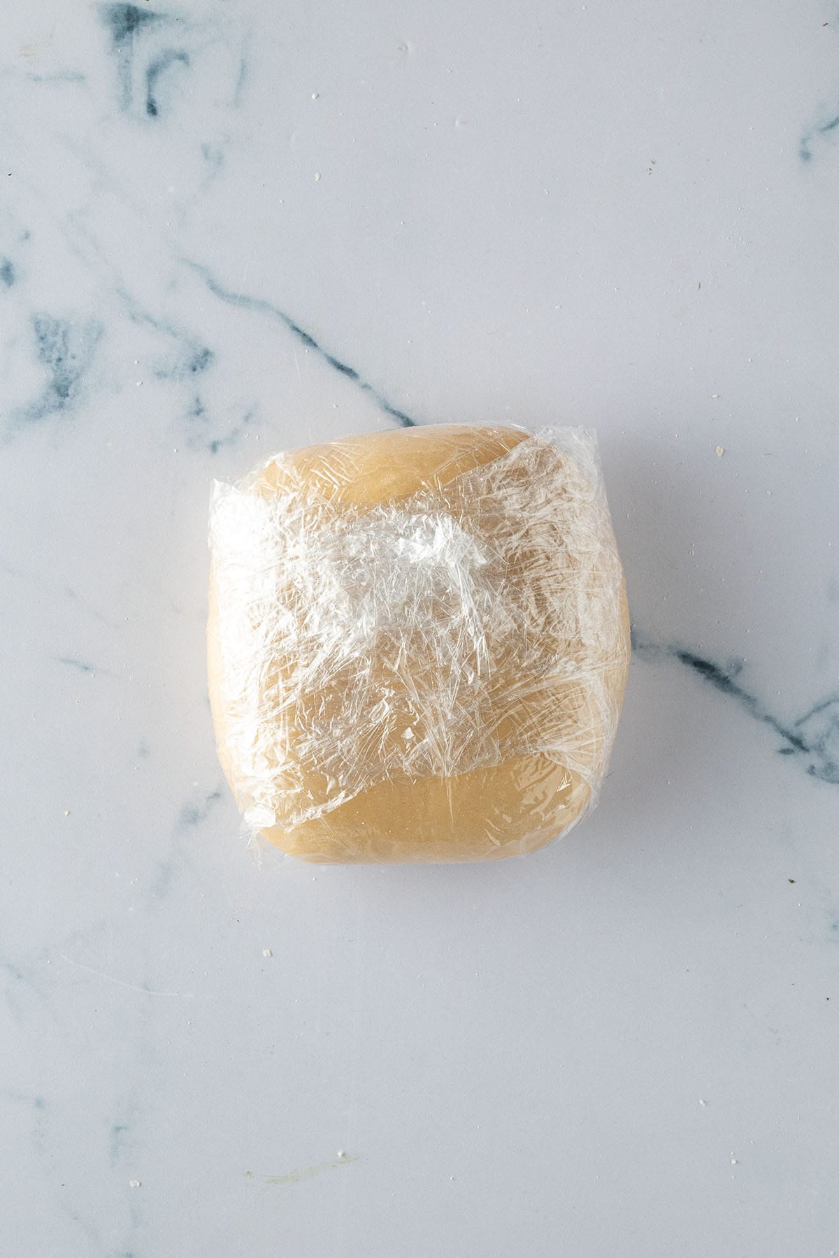 Selbstgemachter Pastateig in Frischhaltefolie eingewickelt zum Ruhen.
