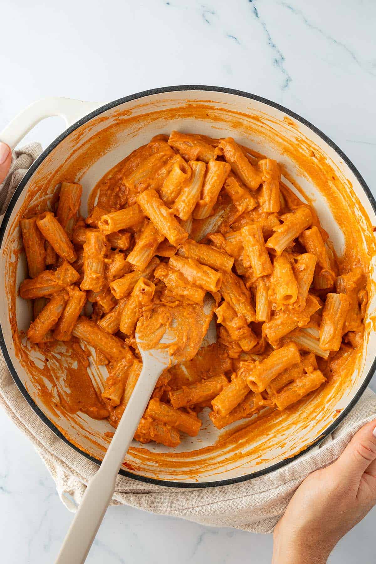 Zwei H&auml;nde halten eine gro&szlig;e Pfanne mit Penne alla Vodka.