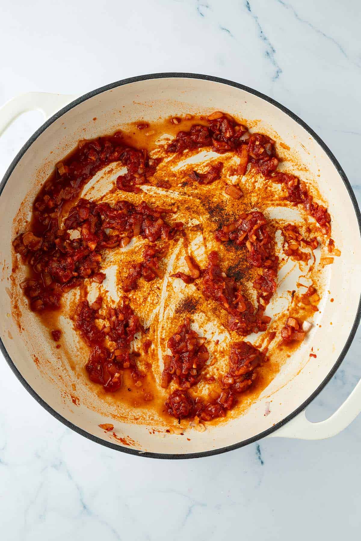 Pfanne mit Zwiebeln, Knoblauch und Tomatenmark, die mit Vodka abgel&ouml;scht wurde.