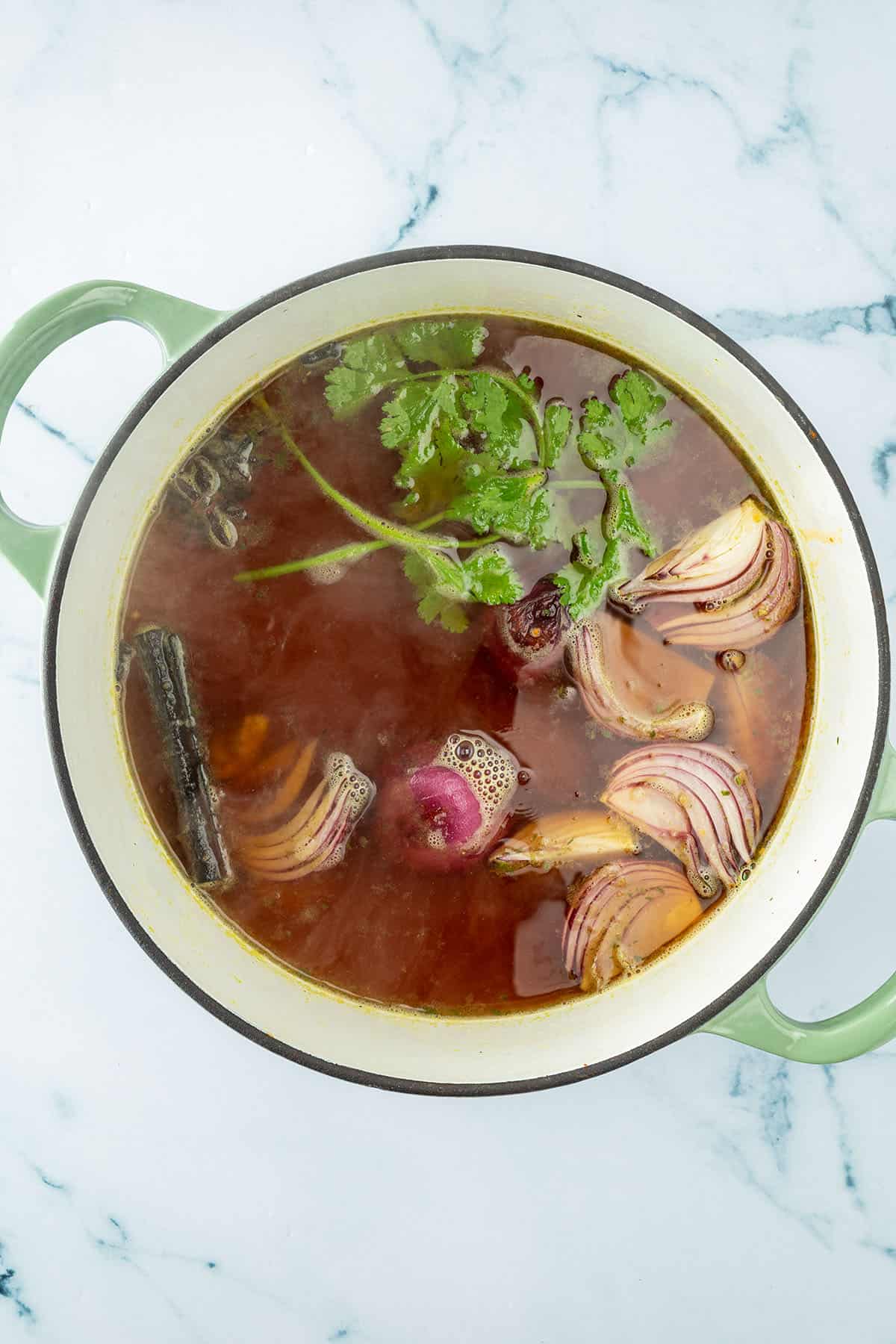 Alle Zutaten f&uuml;r die Pho Br&uuml;he kochen in einem gro&szlig;en Topf.