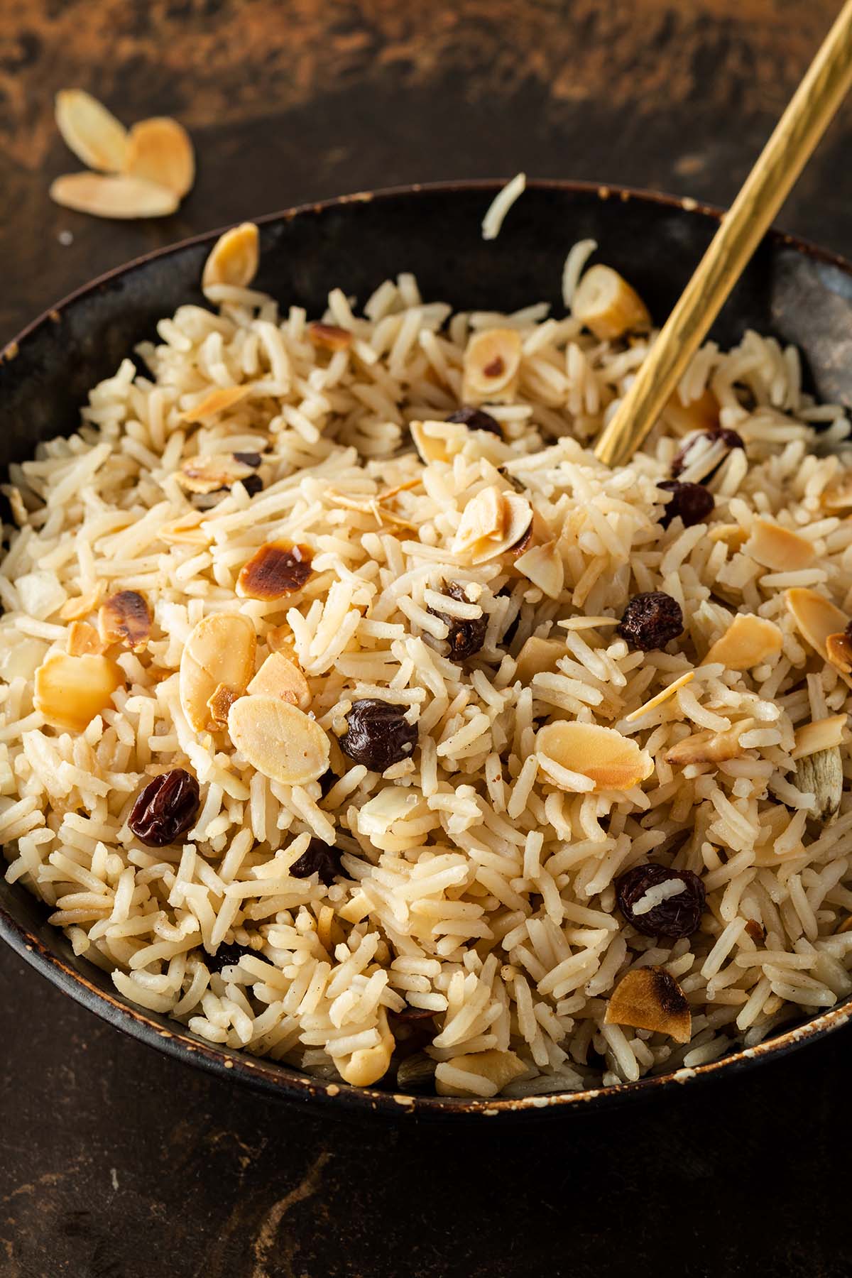 Nahaufnahme von einer Sch&uuml;ssel mit lockerem Basmati Reis mit Rosinen und Mandeln.