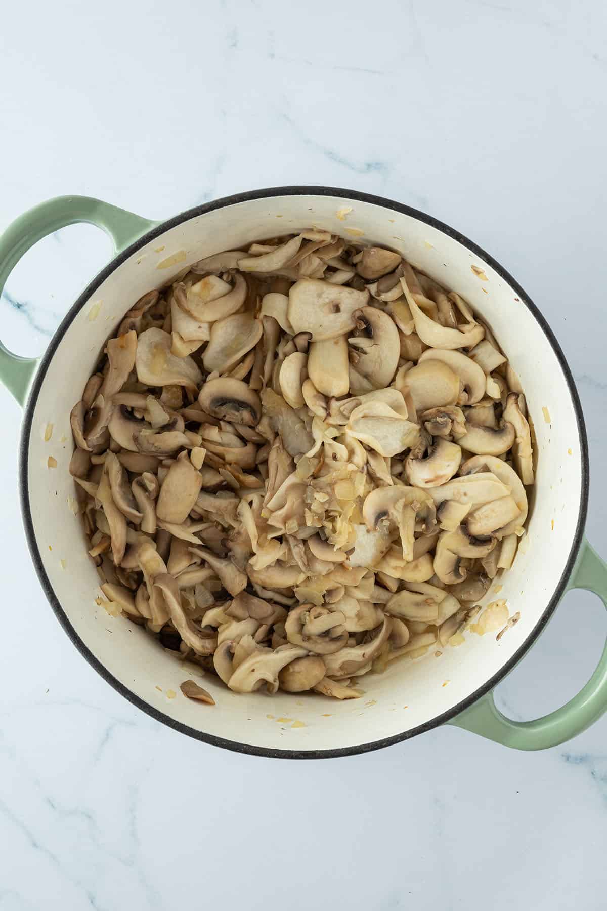 Weich angebratene Pilze und Zwiebeln in einem Topf.