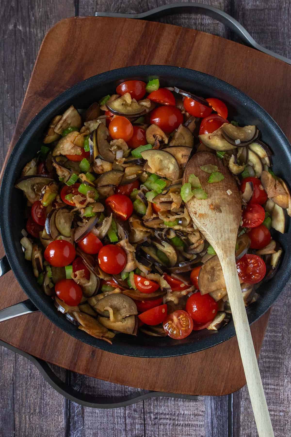Angebratene Aubergine, Sellerie und Tomaten in einer Pfanne.