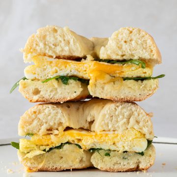 Ein &uuml;bereinander gestapeltes Bagel Sandwich mit Ei und Rucola.