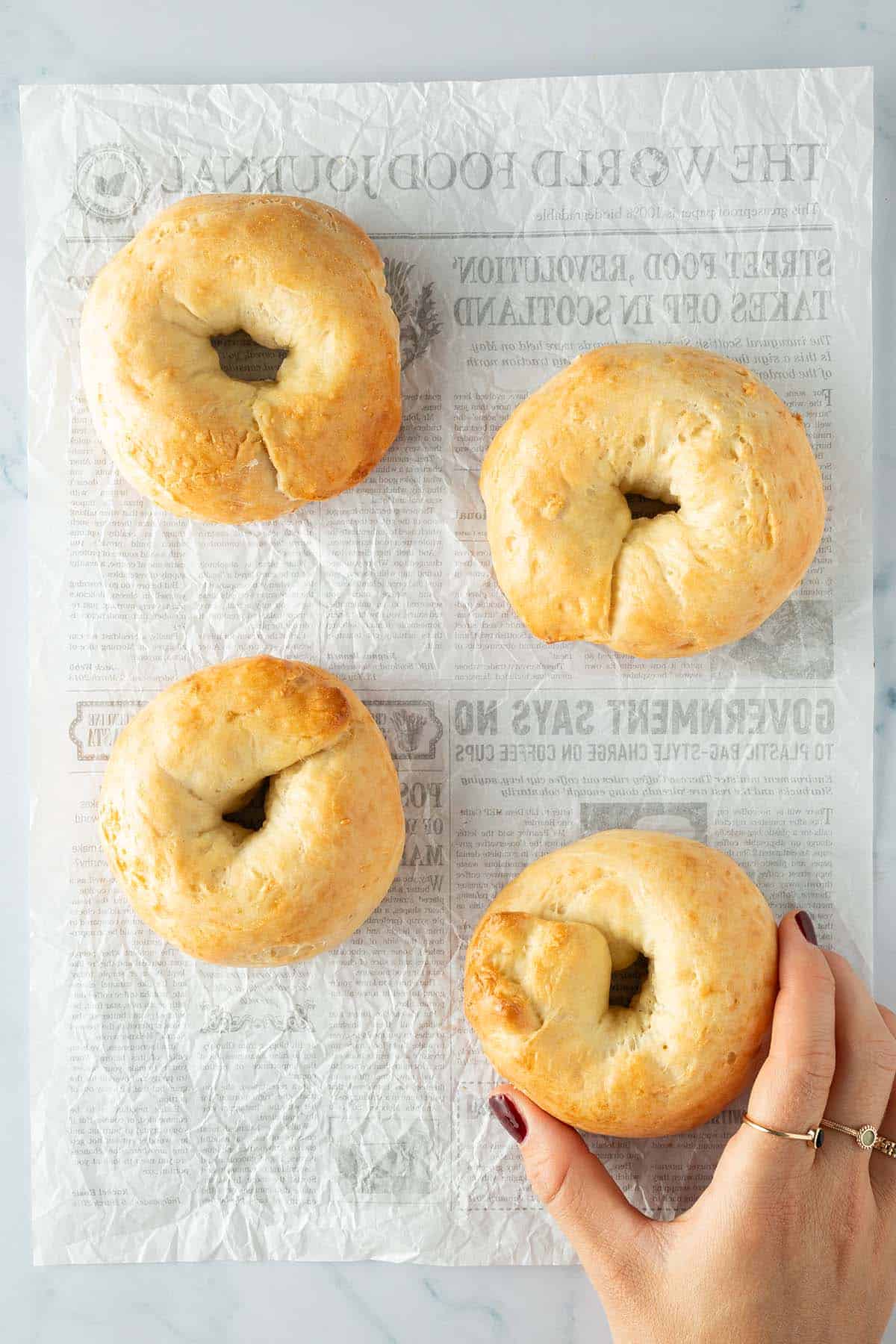 Vier goldbraun gebackene Protein Bagel auf hellem Untergrund.