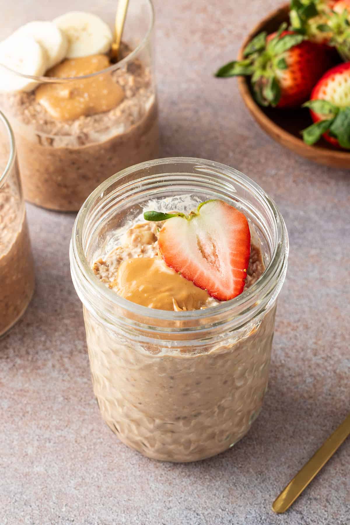 Drei Gl&auml;schen mit Protein Overnight Oats und frischem Obst.