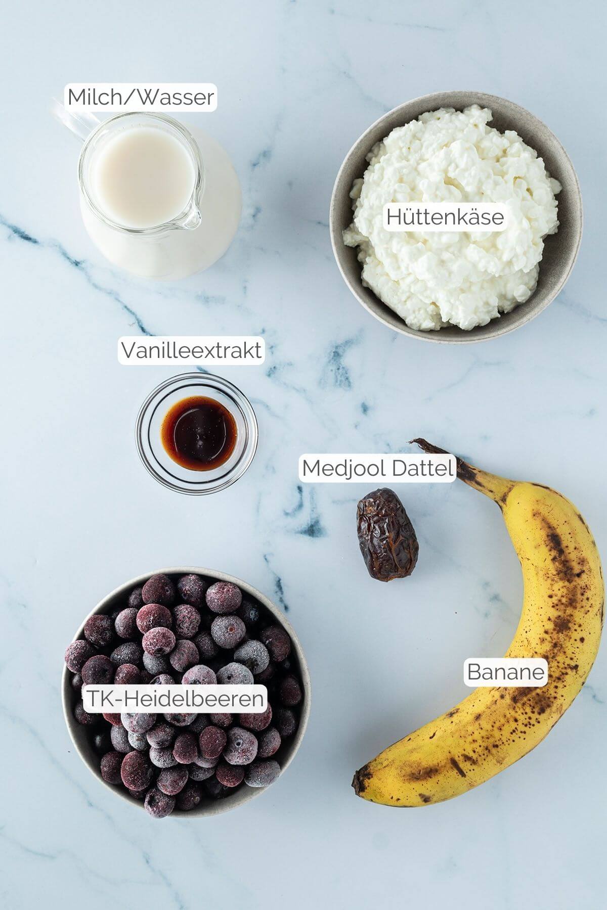 Foto aller Zutaten mit jeweiligen Textbeschriftungen, die f&uuml;r einen fruchtigen Proteinshake ohne Proteinpulver ben&ouml;tigt werden.