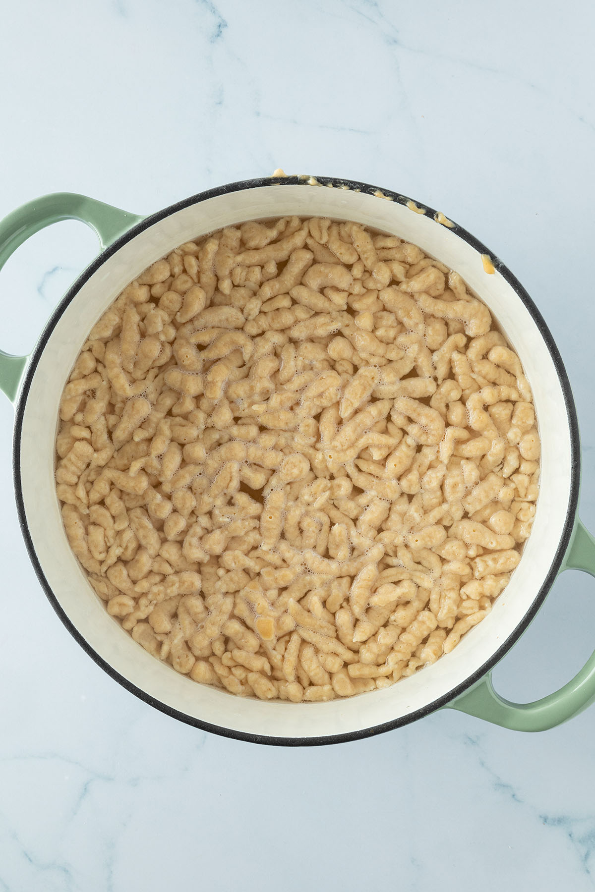 Sp&auml;tzle in einem Topf mit Wasser, die an der Oberfl&auml;che schwimmen.