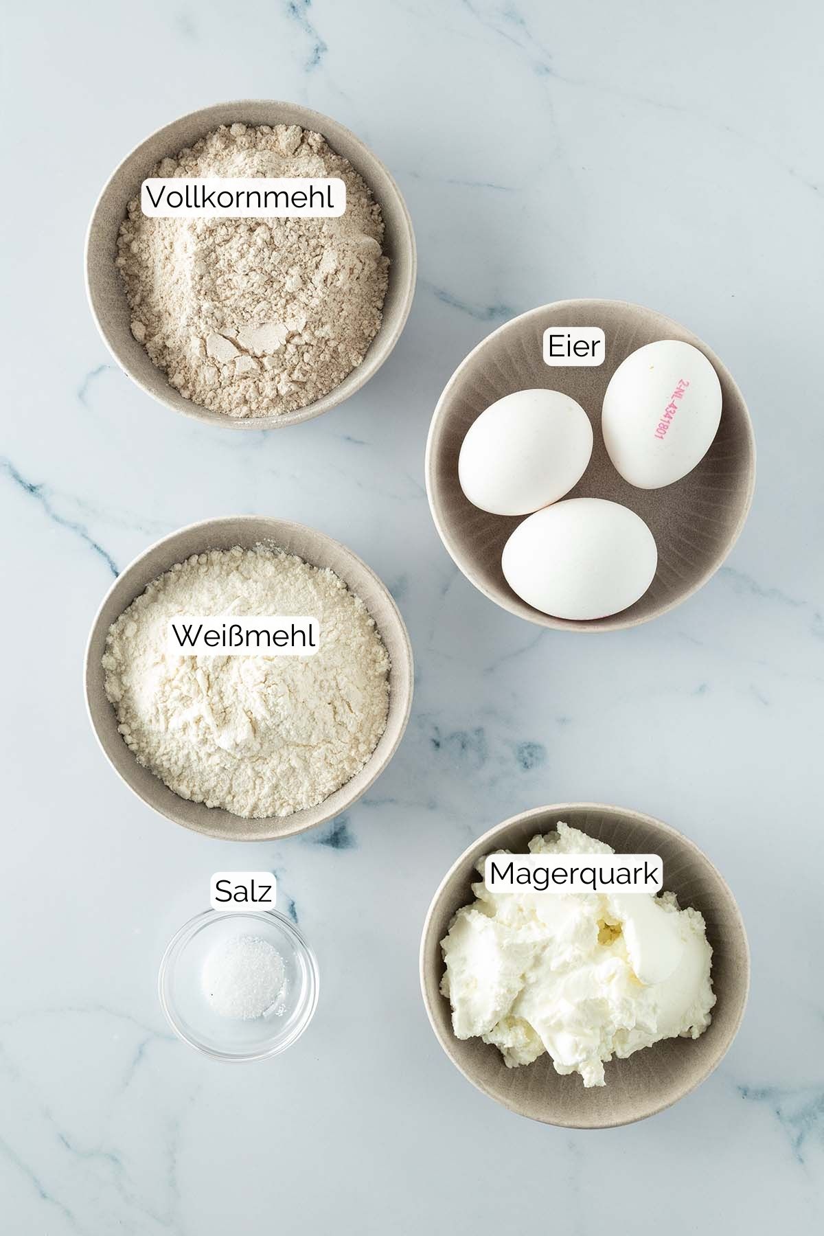 Foto aller Zutaten mit jeweiligen Textbeschriftungen, die f&uuml;r Quarksp&auml;tzle ben&ouml;tigt werden.
