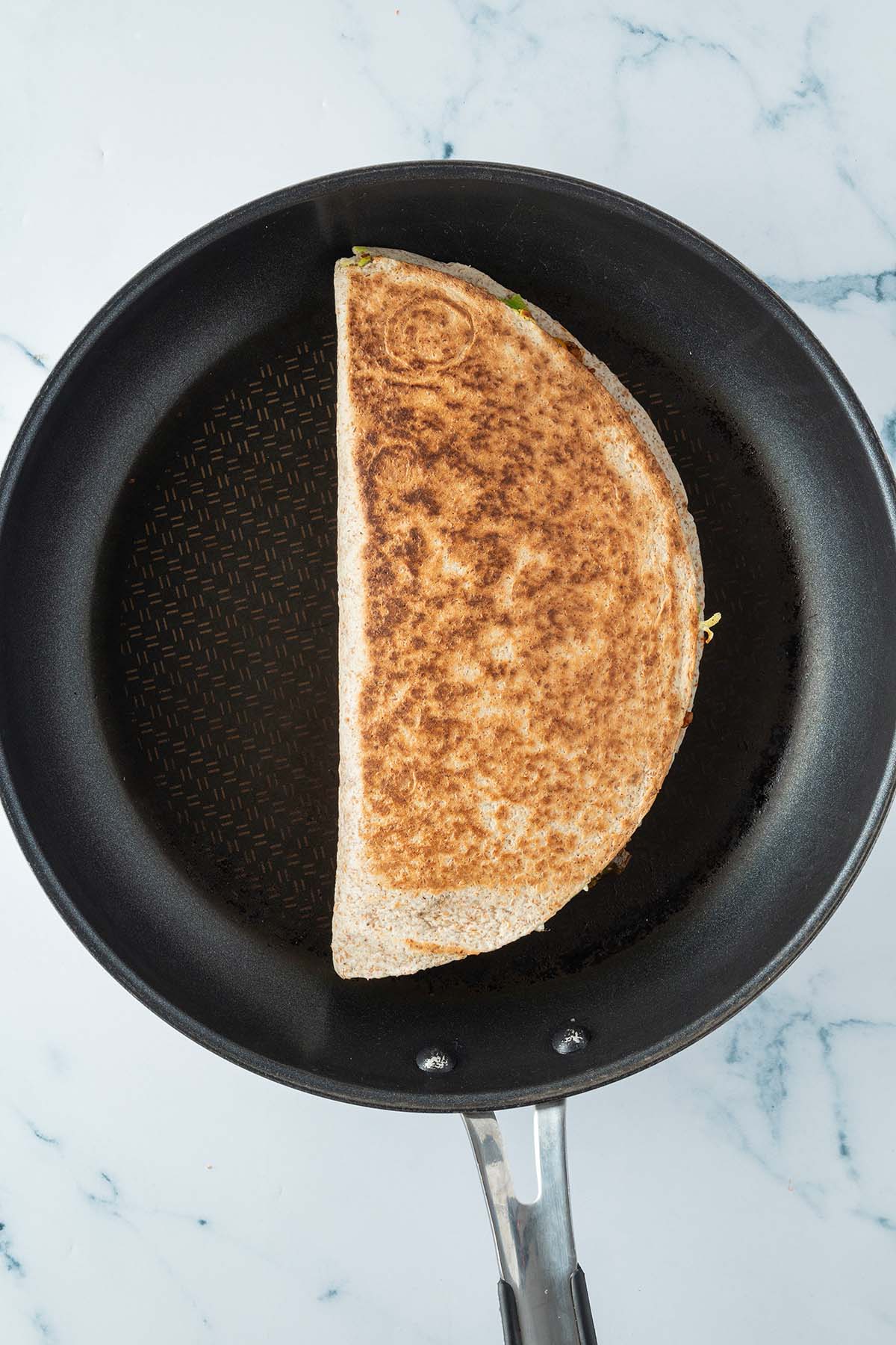 Goldbraun angebratener Quesadilla in einer Pfanne.